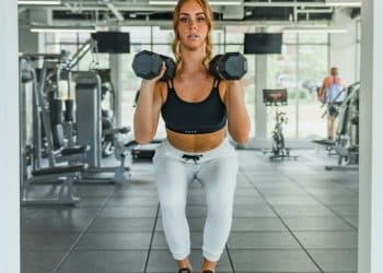 a woman standing on a block with a pair of dumbbells