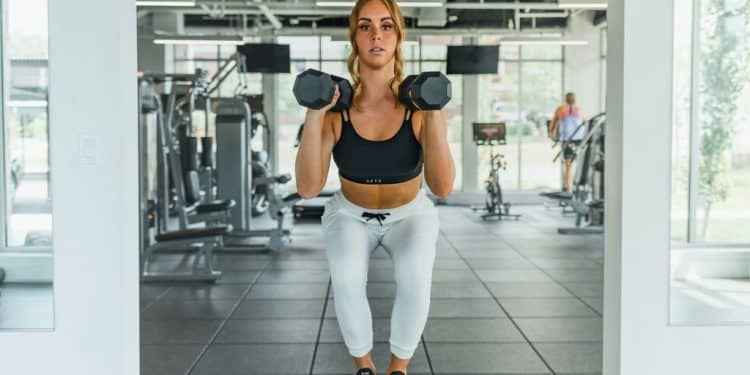 a woman standing on a block with a pair of dumbbells